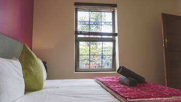 A bedroom with a bed, pillows, a window, and a door.