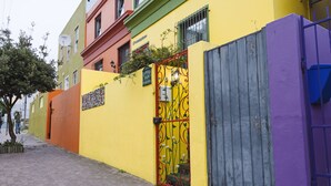 A narrow street with colorful buildings, a gated entrance, and a paved walkway. - La Rose B&B (Cape Town)