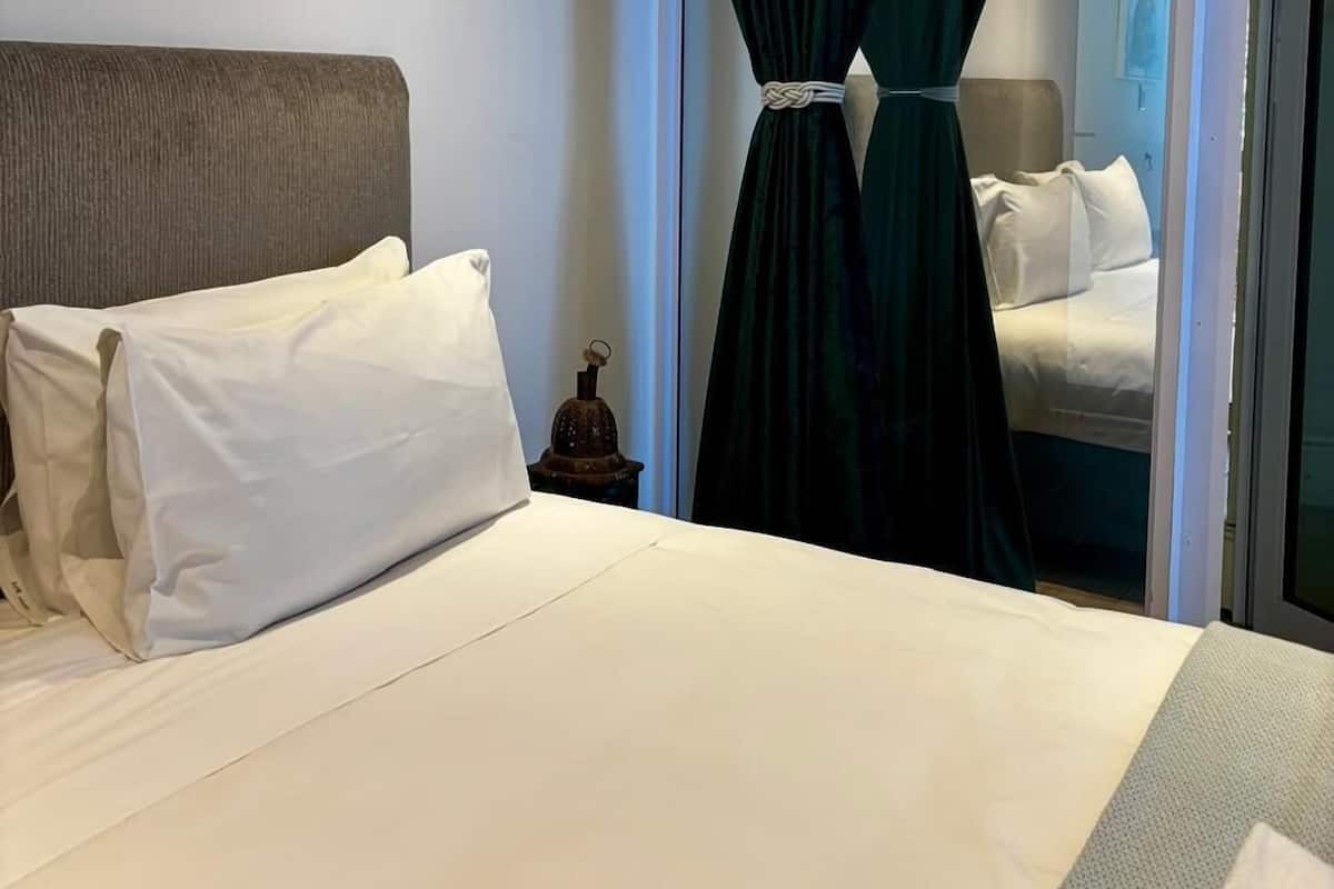 A hotel room with a bed, a nightstand, and a curtain.
