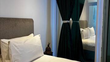 Ein Hotelzimmer mit einem Bett, einem Nachttisch und einem Vorhang.