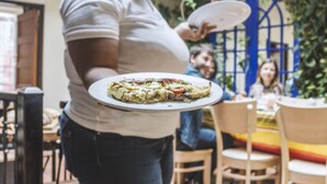 A person holding a plate with food in a courtyard with outdoor seating and a balcony. - La Rose B&B (Cape Town)