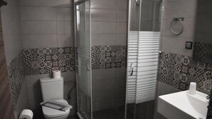A bathroom with a toilet, a shower enclosure, and a sink. - Christina Apts and Studios (Corfu)