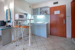 A compact kitchen with a microwave, sink, and bar stools.