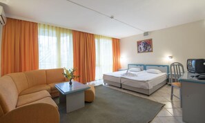 A hotel room with a sofa, a bed, a desk, and a television.
