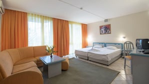 A hotel room with a sofa, a bed, a desk, and a television. - Iskar (Nessebar)