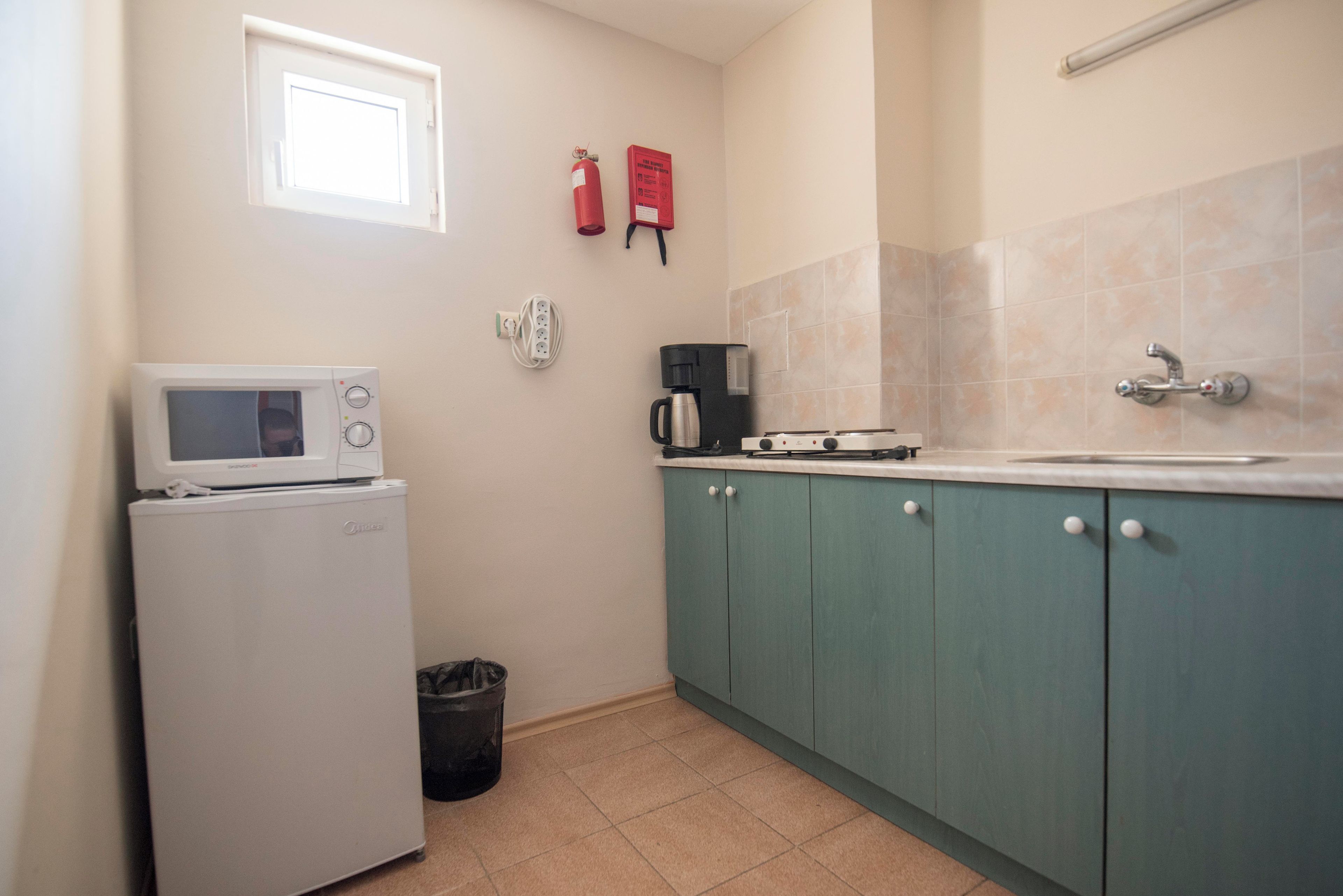 A compact kitchen with a white refrigerator, a coffee maker, and a sink.