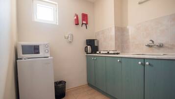 A compact kitchen with a white refrigerator, a coffee maker, and a sink.