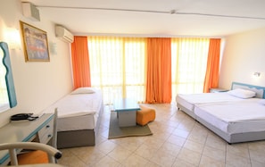 Une chambre d’hôtel avec deux lits, un bureau, une chaise et une fenêtre avec des rideaux orange.