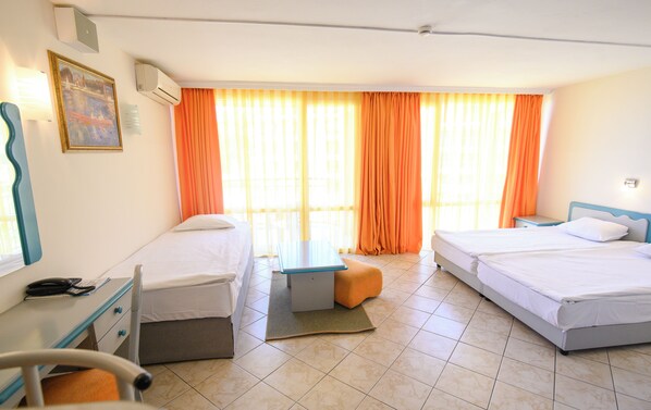 A hotel room with two beds, a desk, a chair, and a window with orange curtains. - Iskar (Nessebar)