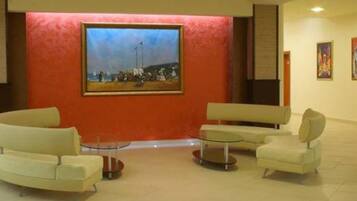 A lobby with a large painting, two sofas, and a small table.