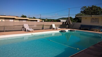 Una piscina al aire libre, sillones reclinables de piscina