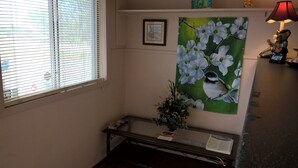 A room with a window, a framed picture, a lamp, and a bench. - Dogwood Motel (Mountain View)