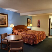 Una habitación de hotel con una cama, un escritorio, dos sillas y un cuadro en la pared.