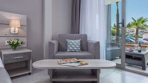 A modern living room with a grey sofa, a side table with a lamp, and a magazine on a coffee table. - Dionysos Hotel and Studios (Kassandra)