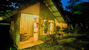 Une cabane en bois avec une véranda, une chaise et un petit jardin.