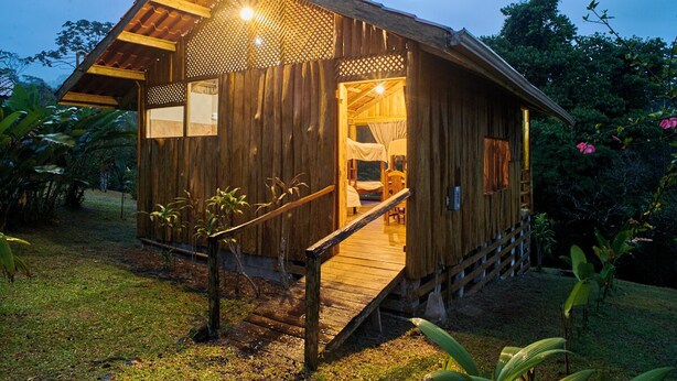 Une cabane en bois avec une véranda, un lit et une petite table.
