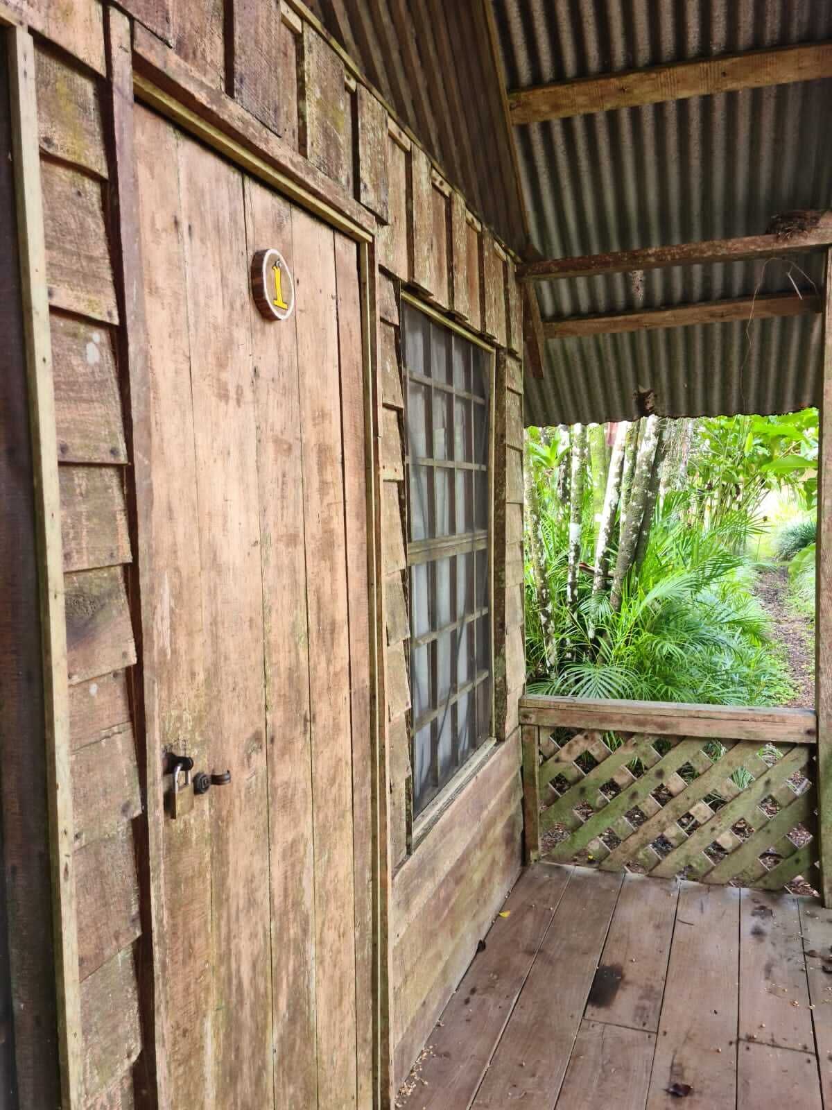 A rustic wooden door with a window, a metal latch, and a small circular sign.