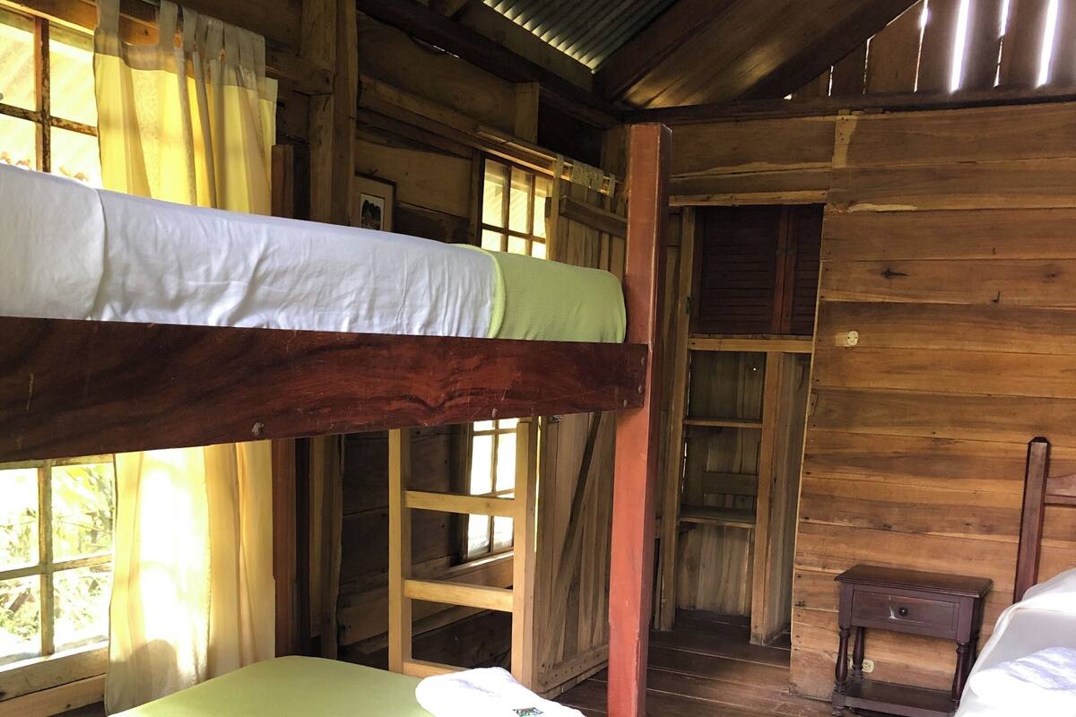 A rustic cabin with two bunk beds, wooden floors, and a small wooden table.