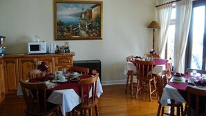 Un espace repas avec des meubles en bois, un tableau accroché au mur et une vue sur l’extérieur.