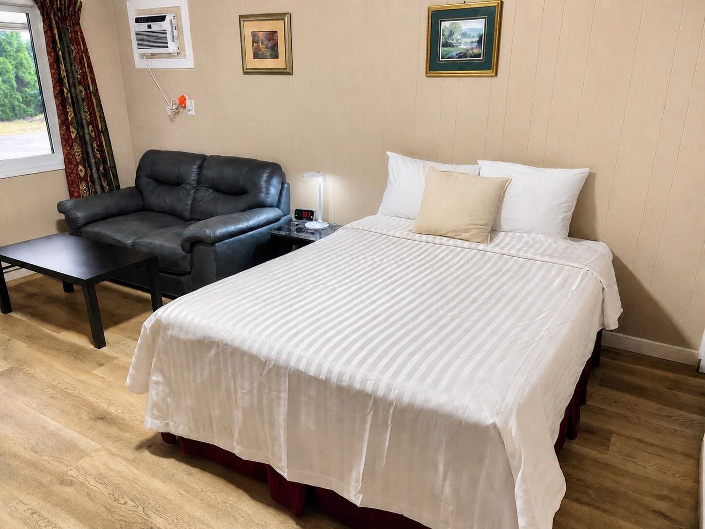 Une chambre d’hôtel avec un lit, une chaise, une table de chevet et une fenêtre.