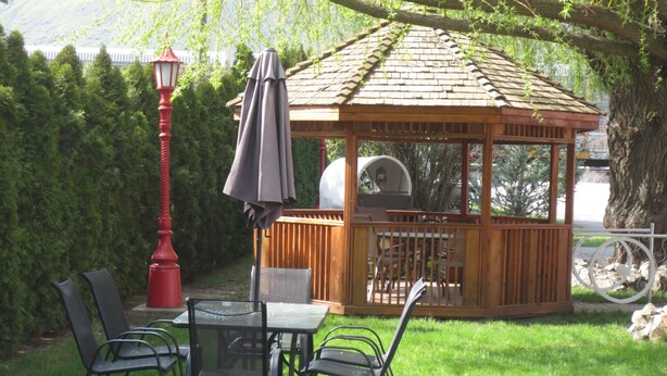 A gazebo with a tiled roof, surrounded by a wooden fence, and a red lamp post nearby. - Overlander Motel (Chase)