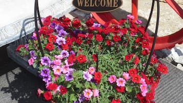 A welcome sign with a flower planter in front of a red metal bench.