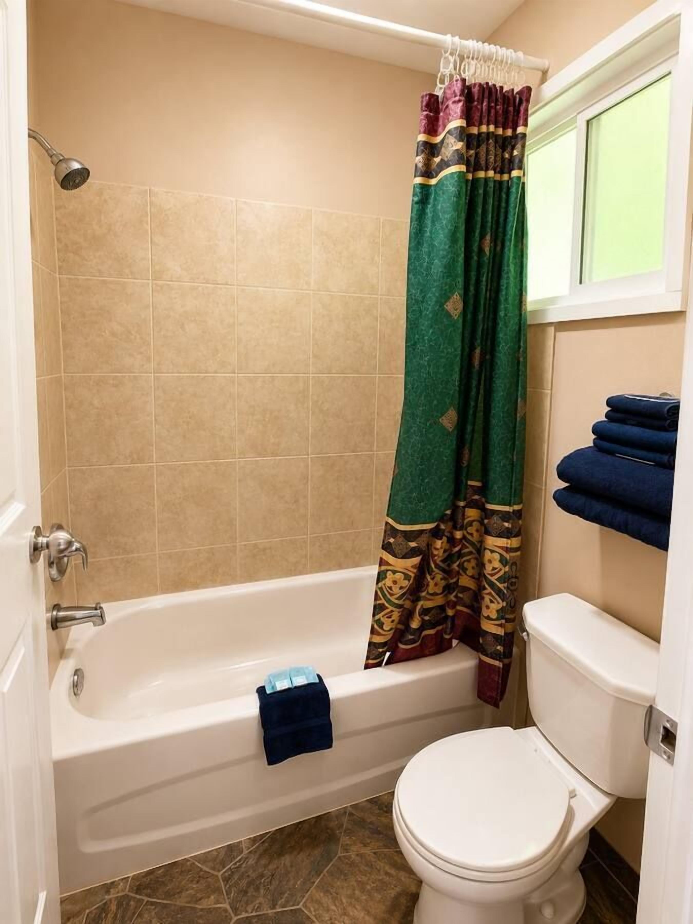 A bathroom with a bathtub, toilet, and a shower curtain.