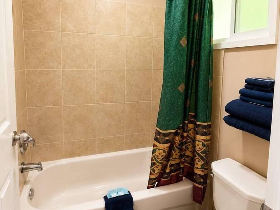 A bathroom with a bathtub, toilet, and a shower curtain.