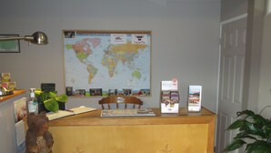 A reception desk with a world map, a wooden bear sculpture, and a plant. - Overlander Motel (Chase)
