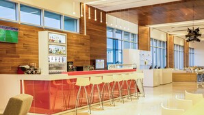 A modern hotel lobby with a reception desk, bar area, and seating.