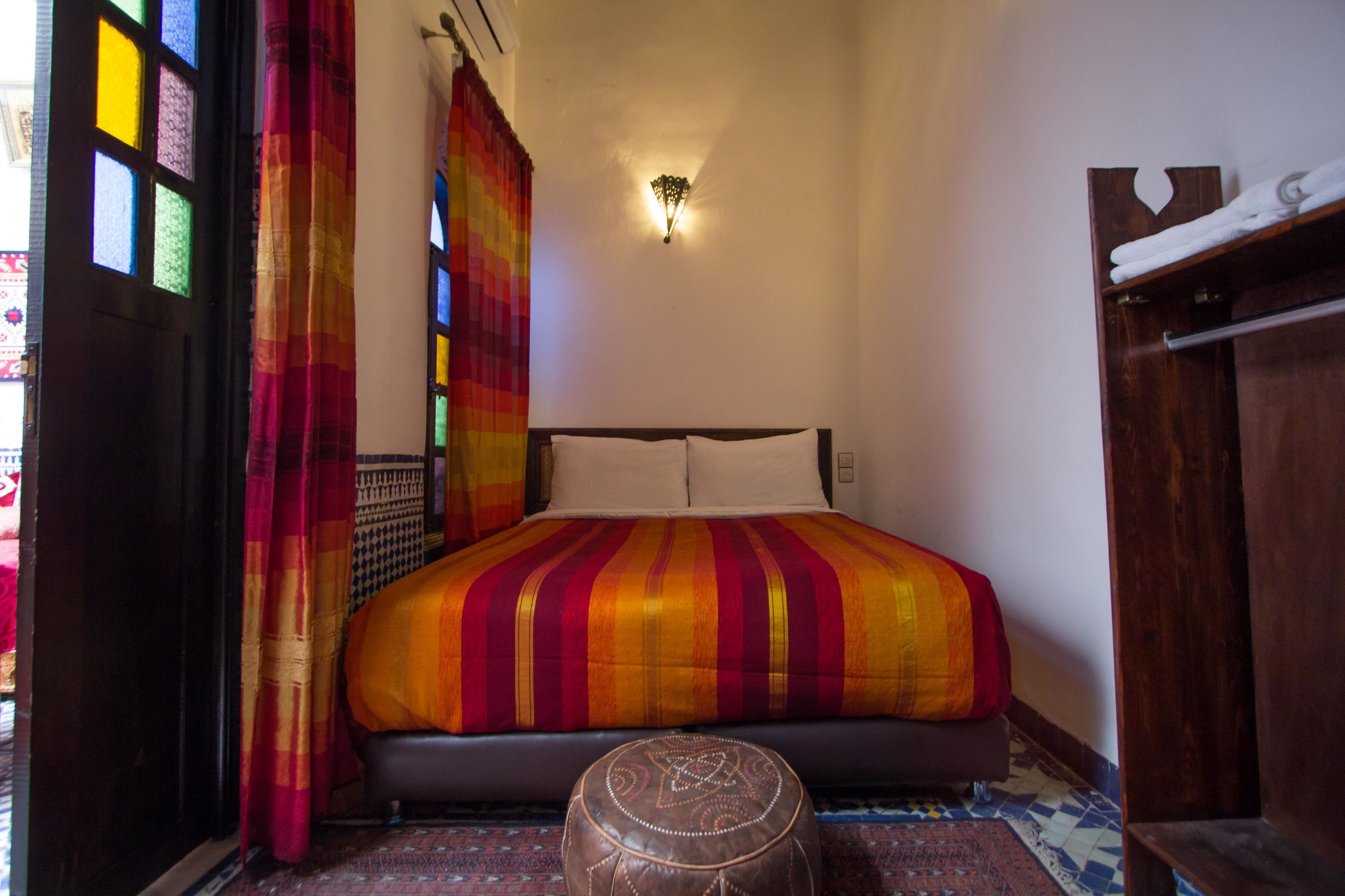 A bedroom with a large bed, a wooden bench, and a patterned rug.