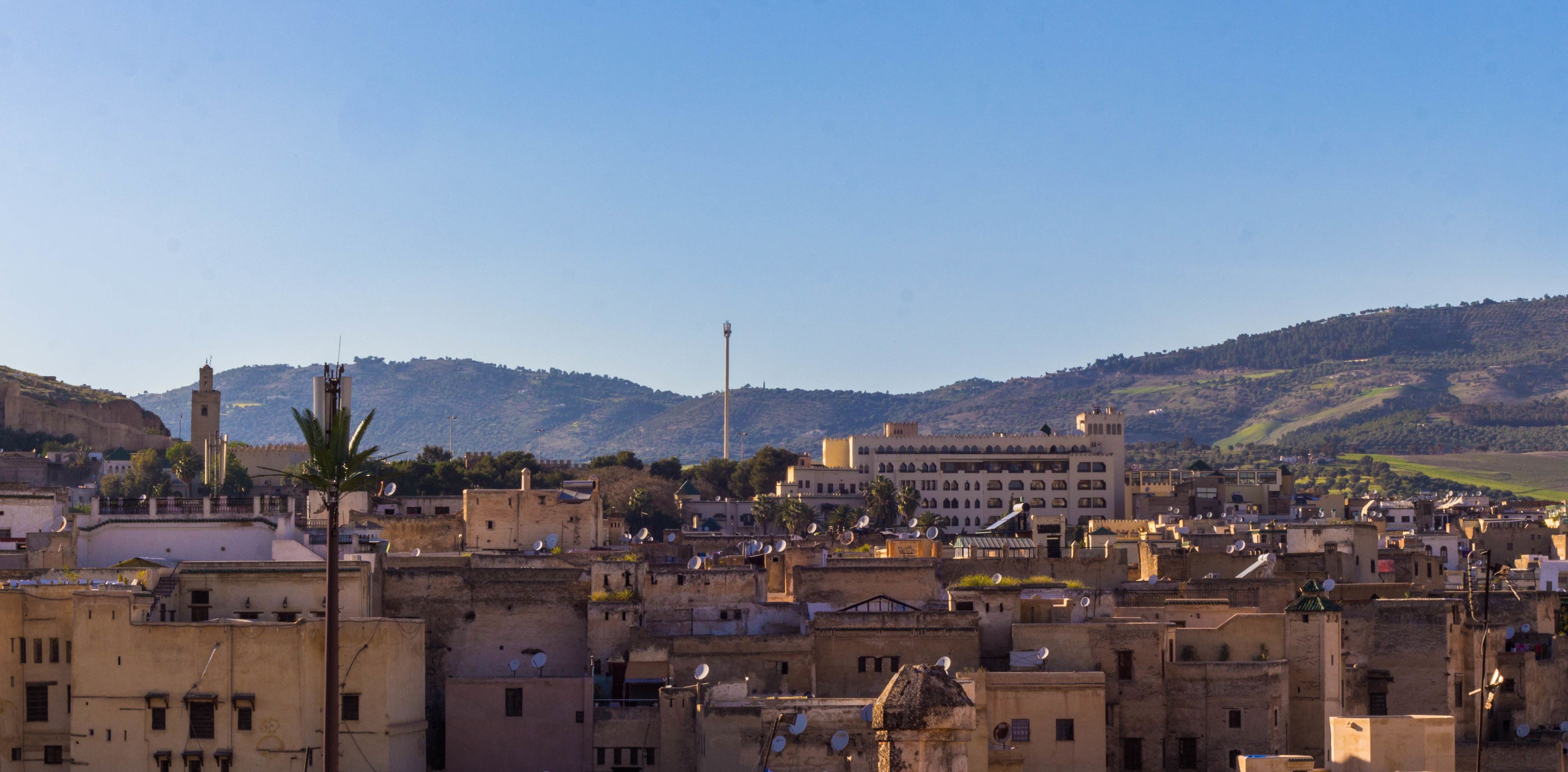 A densely packed urban area with traditional architecture, including flat-roofed buildings and a prominent mosque with a minaret.