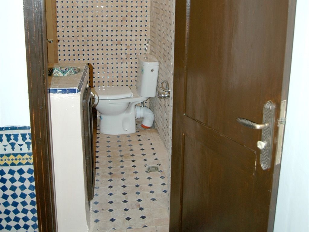 A small bathroom with a toilet, a sink, and a shower. The floor has a patterned tile design.