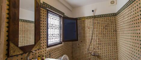 A bathroom with a sink, mirror, and shower.