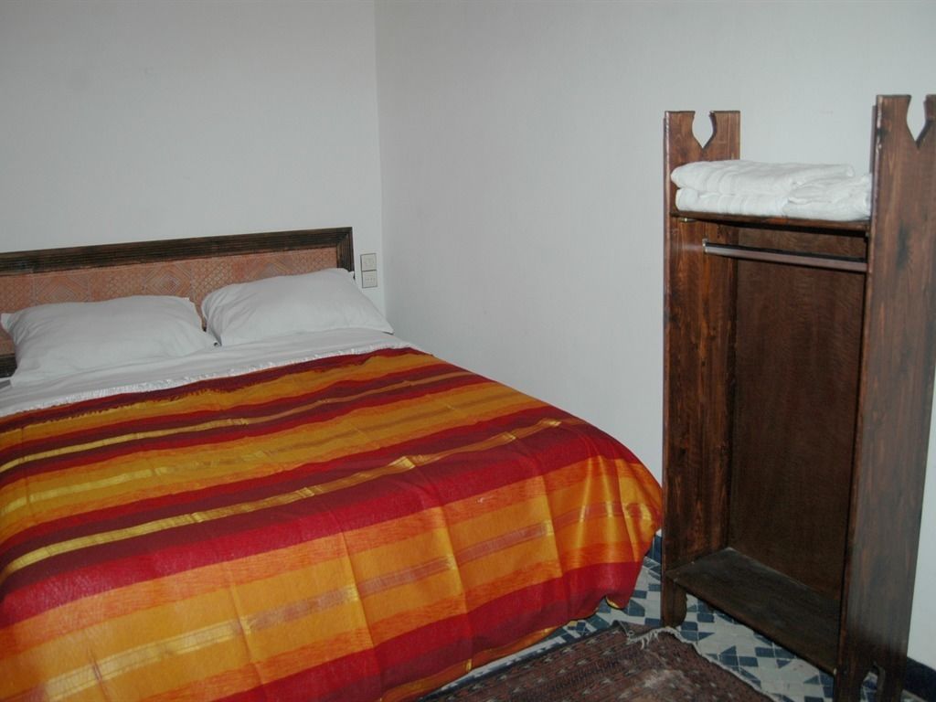 A bed with a striped blanket, a wooden headboard, and a wooden wardrobe with a mirror.