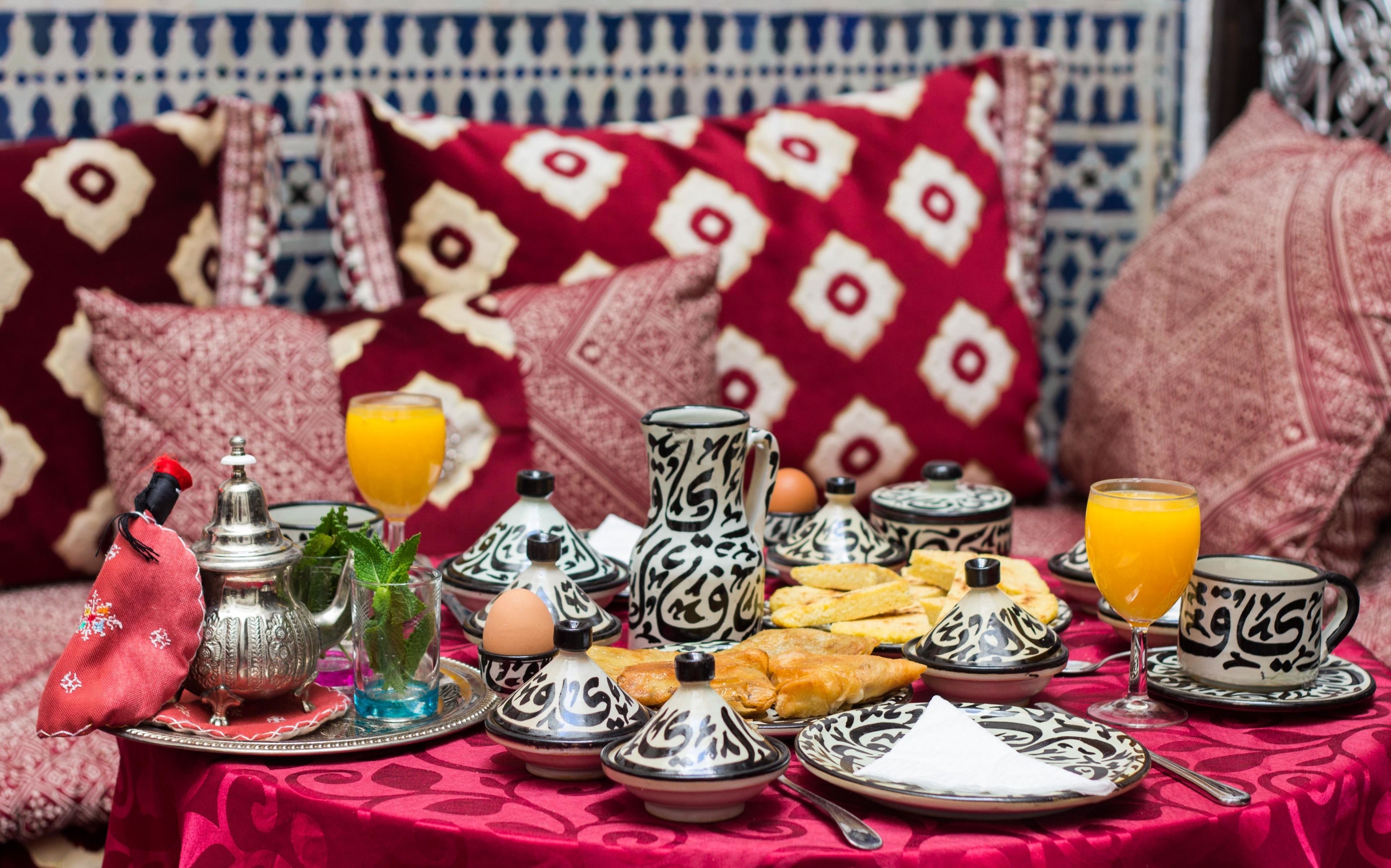 A traditional Moroccan breakfast spread on a red tablecloth with a patterned background.