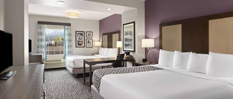 A hotel room with a large bed, a smaller bed, a desk, and a TV.