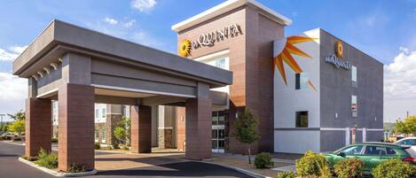 A hotel with a modern design, featuring a prominent entrance with a covered area and a large sign displaying the hotel name.