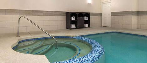 A swimming pool with a tiled edge, a metal ladder, and a towel rack against the wall.