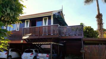 A two-story house with a balcony, a garage with two cars, and a wooden fence.