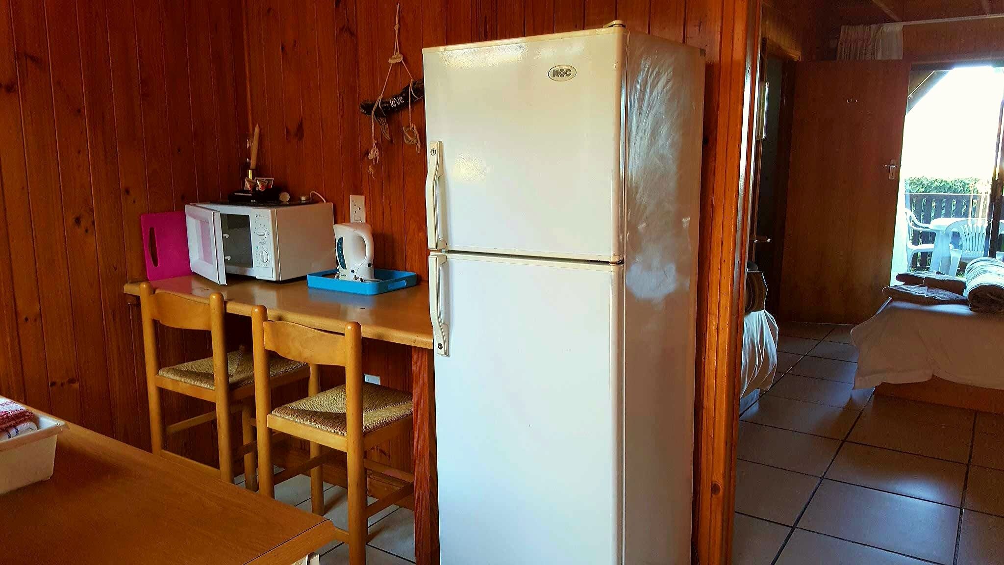 Eine kleine Küche mit einem weißen Kühlschrank, einer Mikrowelle und einem Toaster auf einer Holztischplatte.