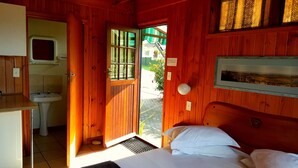 Une pièce en bois avec un lit, un lavabo et une fenêtre.