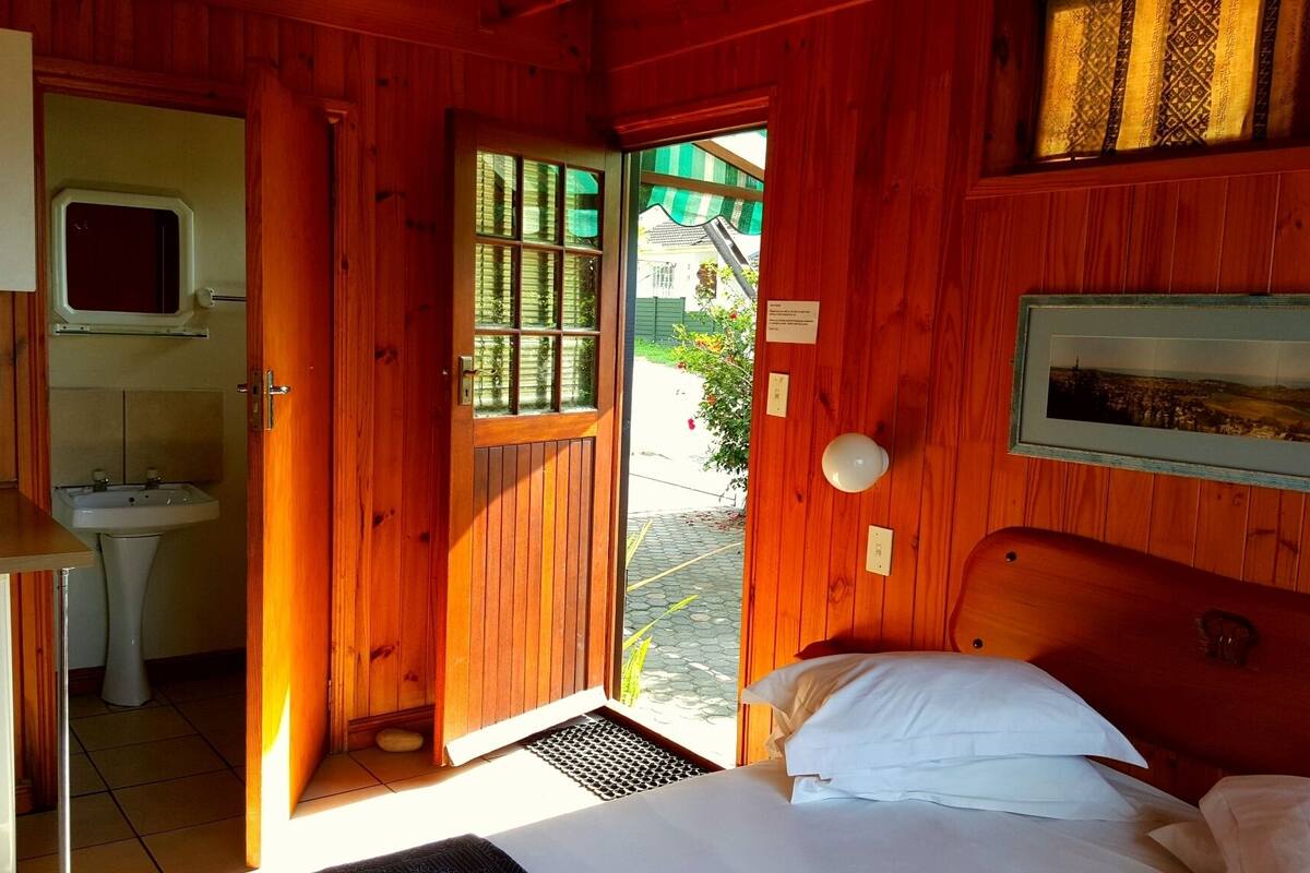 Une pièce en bois avec un lit, un lavabo et une fenêtre.