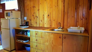 Une cuisine compacte avec des meubles en bois, un four à micro-ondes, un évier et un petit plan de travail.
