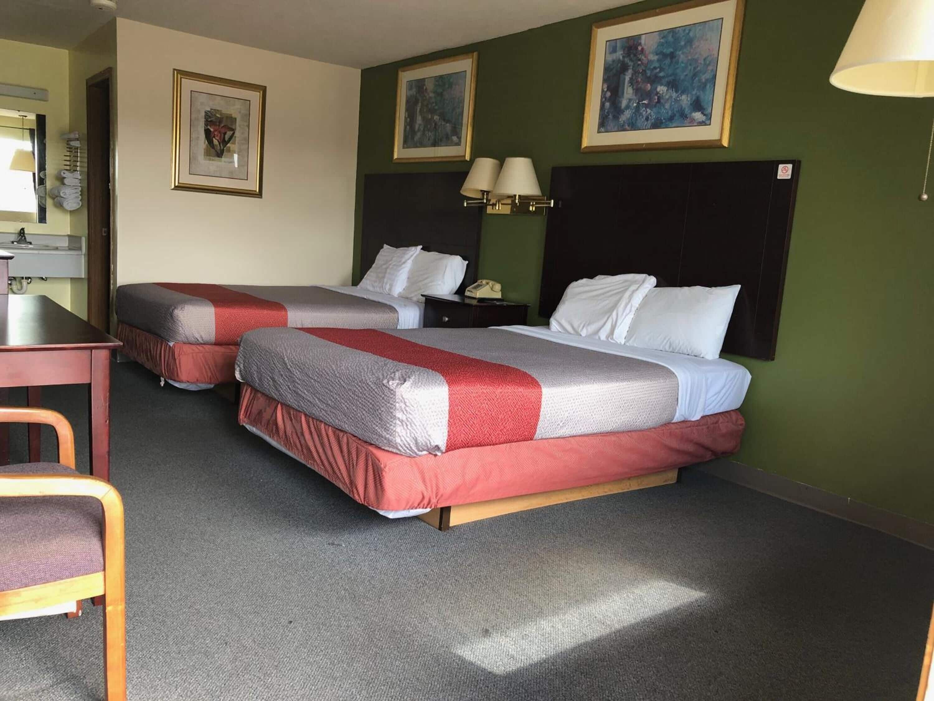 Habitación de hotel con dos camas, un escritorio, una silla y un teléfono.