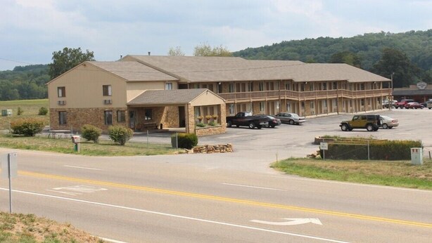 A motel with a two-story structure, a covered front porch, and a parking lot with several cars.
