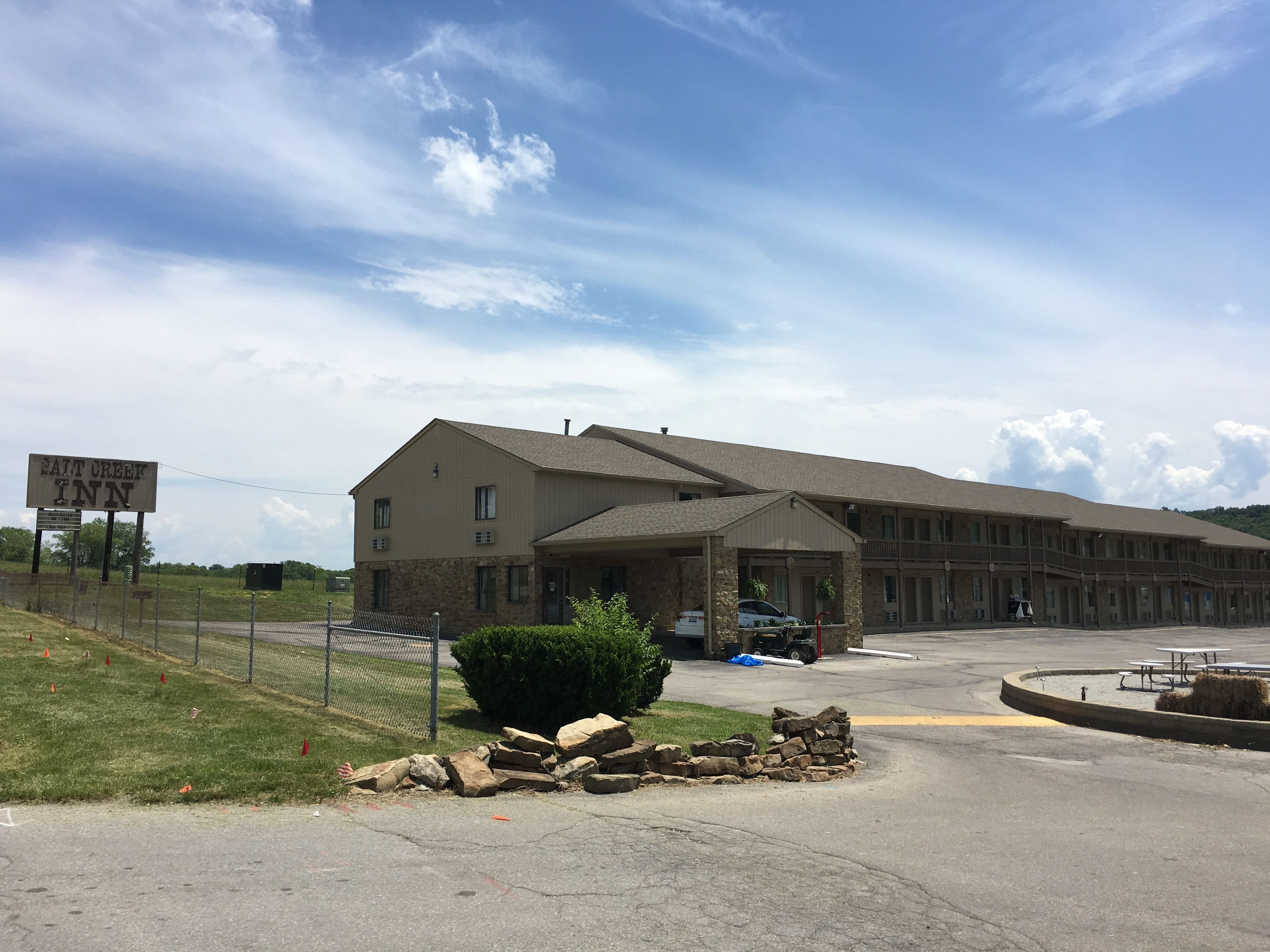 Un motel avec une grande enseigne indiquant « SALT CREEK INN » et un espace de stationnement couvert.