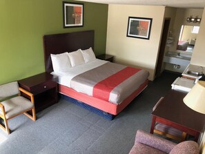 A hotel room with a bed, a desk, a chair, a dresser, and a mirror.