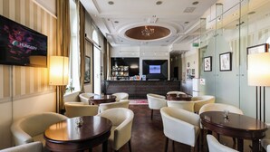 A hotel lobby with a bar area, seating arrangements, and a television screen displaying 'HUNGARY'. - Mirage Medic Hotel (Budapest)