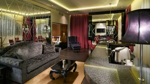 A modern living room with a sofa, armchair, coffee table, and a kitchen area with a kettle and toaster. - Mirage Medic Hotel (Budapest)